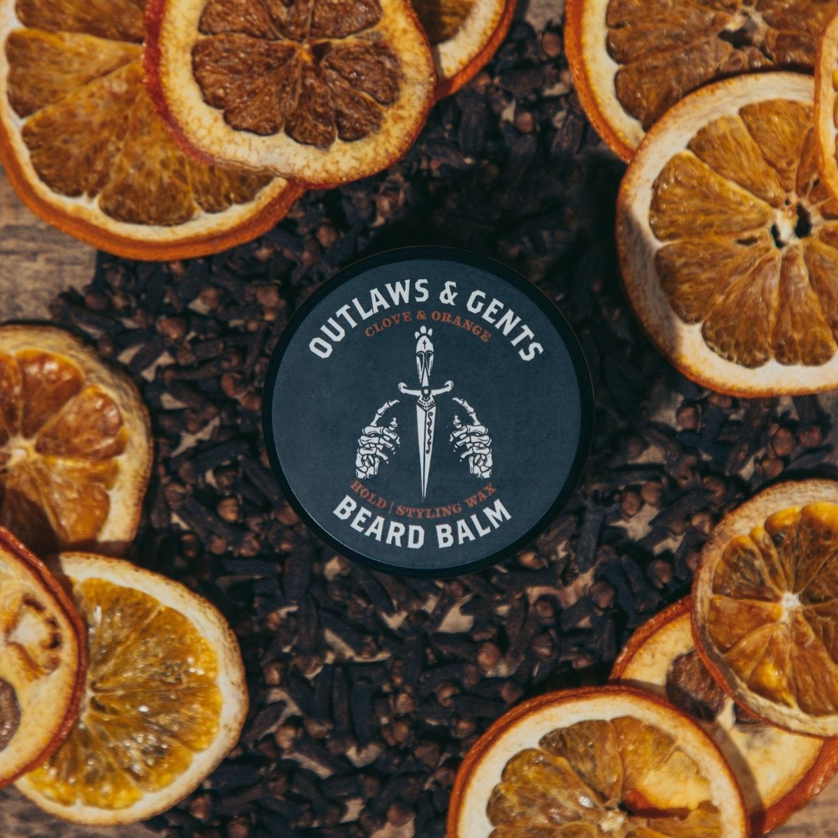 Outlaws and Gents Clove and Orange Beard Balm surrounded by dried oranges