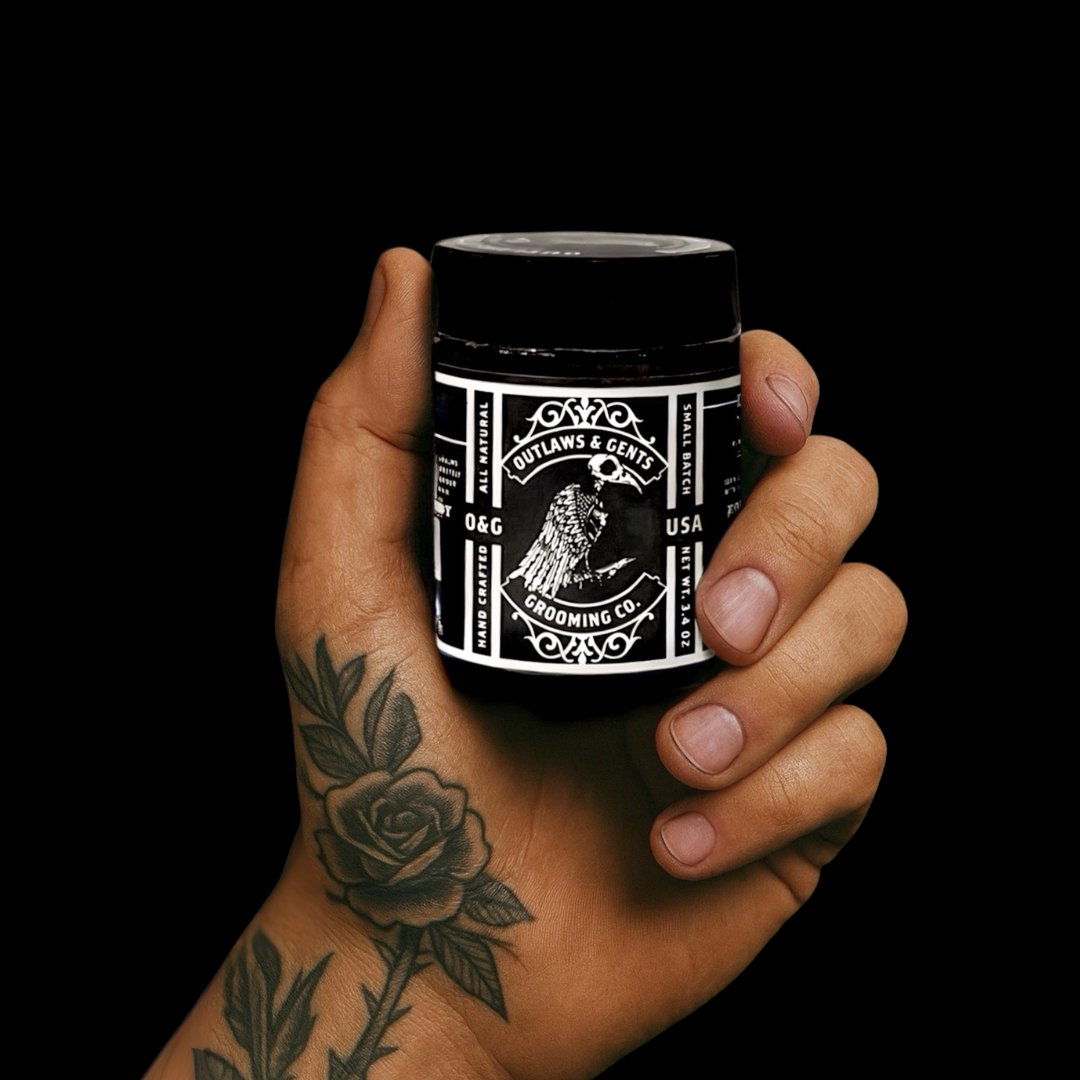 Man’s hand holding Outlaws and Gents tobacco and vanilla beard butter
