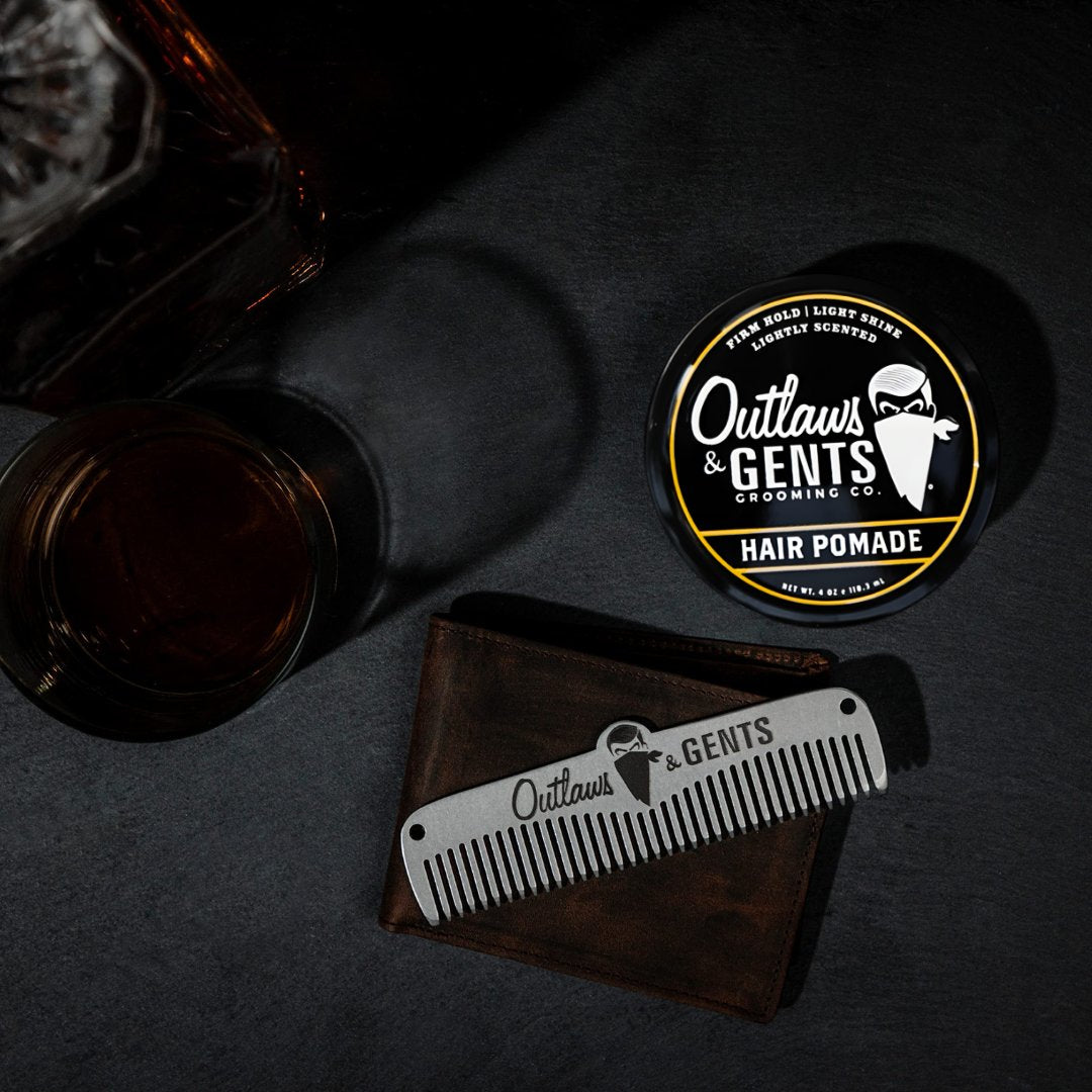 Outlaws and Gents hair pomade with metal comb and a glass of whiskey