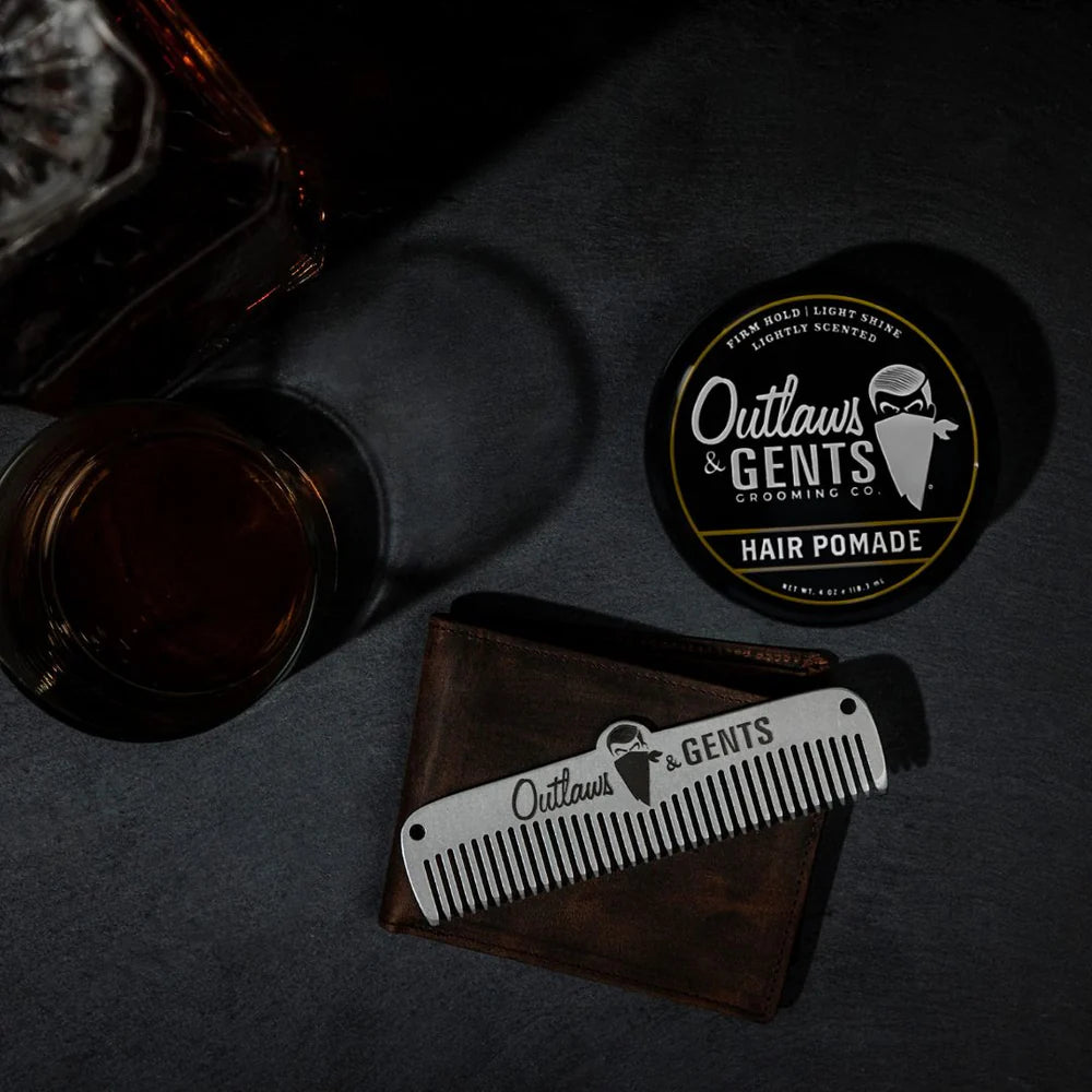 Outlaws and Gents hair pomade with metal comb and a glass of whiskey