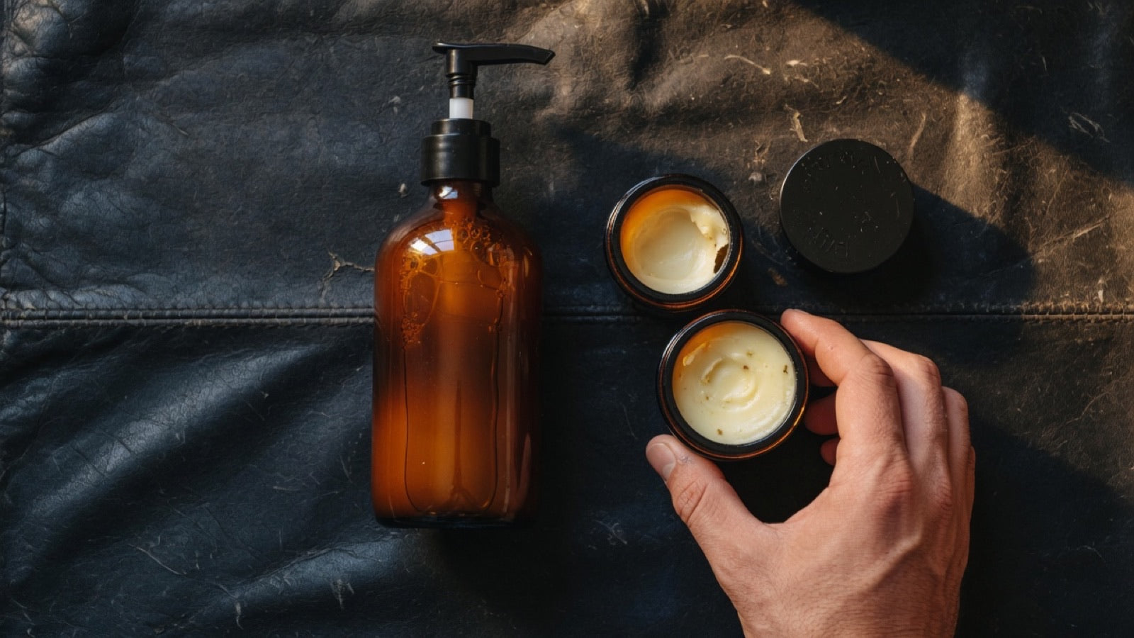 Beard oil dropper bottle, balm tin, and butter jar lined up on dark wood — beard oil vs balm vs butter