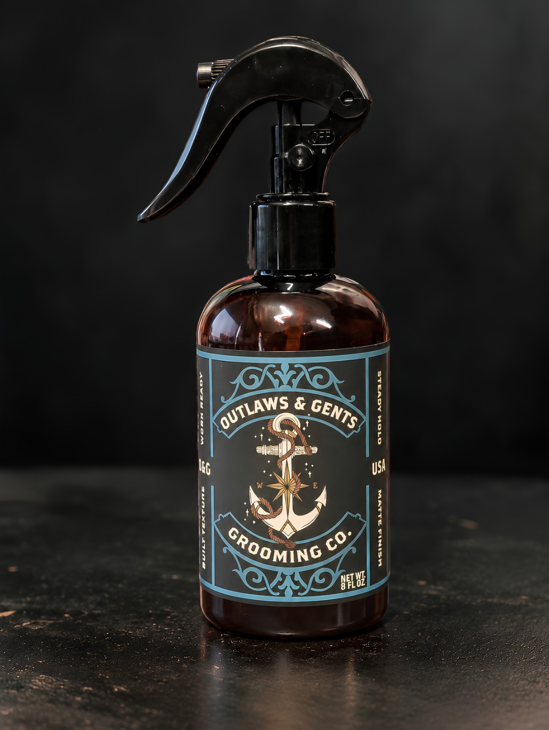 Outlaws and Gents Salt Grit Spray 'Outlaws & Gents Grooming Co.' The bottle is photographed on a dark, textured surface against a dark background.